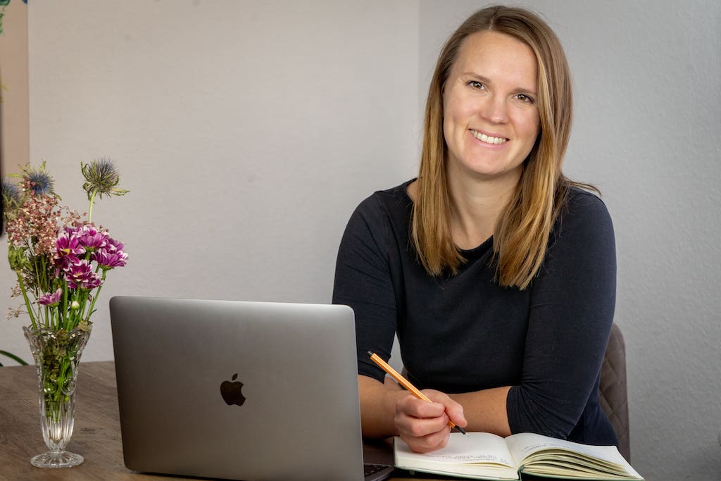 Anna Hopfengärtner, SEO-Expertin, sitzt mit Laptop und Notizbuch am Schreibtisch.
